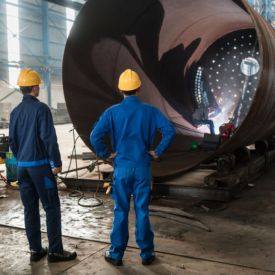 Workers supervising the manufacture of a metallic cylinder